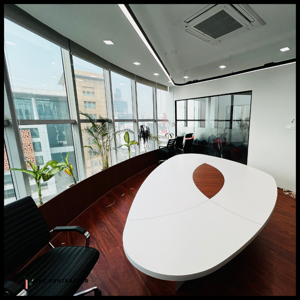 Corporate conference room with oval white walnut table, black chairs, glass walls, and indoor plants.